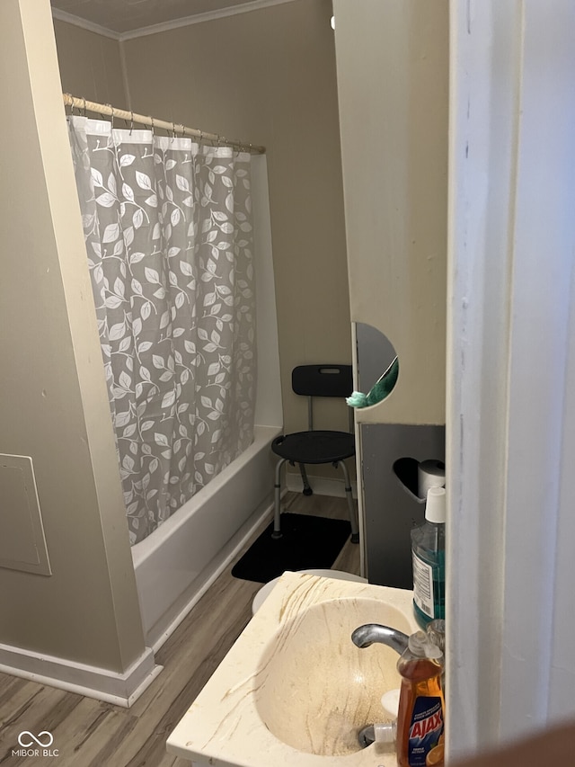 full bath with wood finished floors, crown molding, shower / tub combo with curtain, and a sink