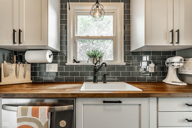 kitchen featuring butcher block countertops, dishwasher, a sink, white cabinetry, and decorative backsplash