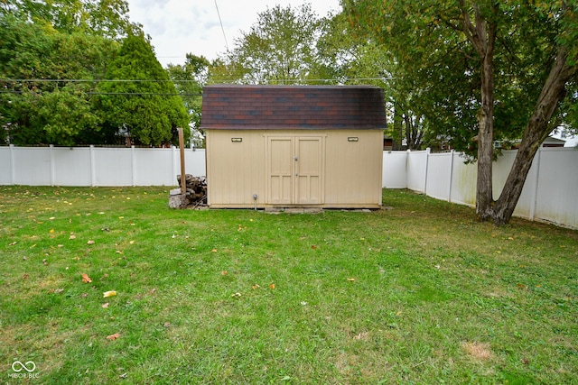 view of yard with a fenced backyard, an outdoor structure, and a storage unit