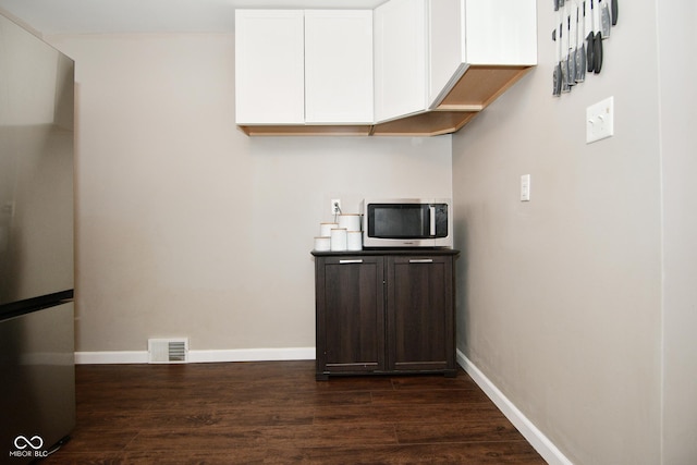 kitchen featuring freestanding refrigerator, white cabinetry, visible vents, baseboards, and dark wood-style floors