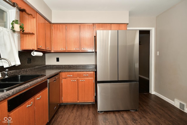 kitchen with a sink, brown cabinetry, visible vents, dark wood-style flooring, and appliances with stainless steel finishes