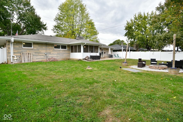 view of yard featuring a fenced backyard, a sunroom, a patio, and a fire pit