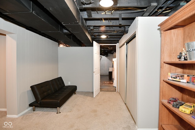 finished basement with freestanding refrigerator and light carpet