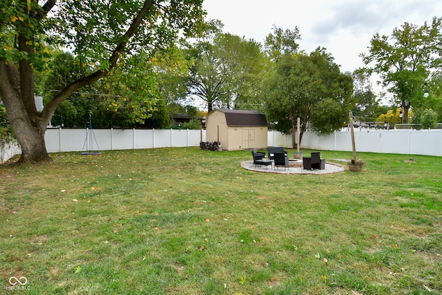 view of yard with a patio, a fire pit, a fenced backyard, a shed, and an outbuilding