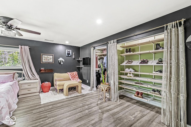bedroom featuring wood finished floors, recessed lighting, a walk in closet, and a closet