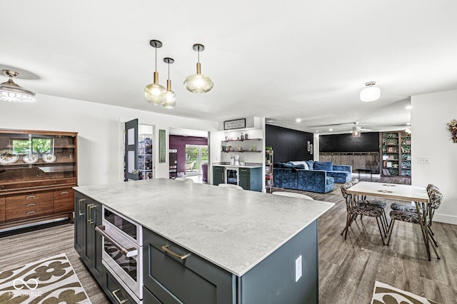 kitchen with wood finished floors, a kitchen island, decorative light fixtures, and oven