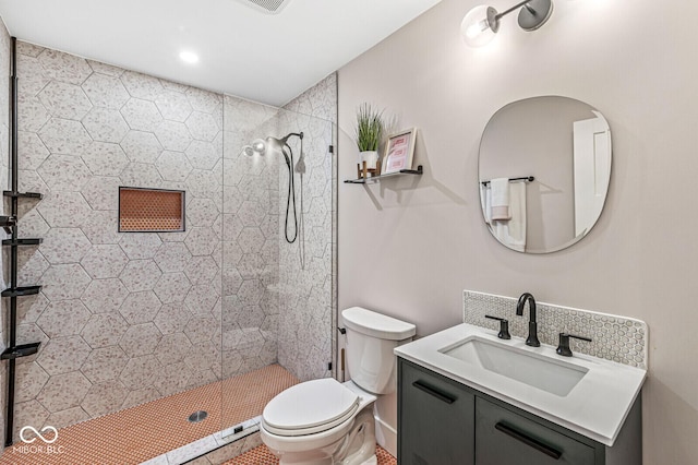 full bathroom featuring toilet, a tile shower, and vanity