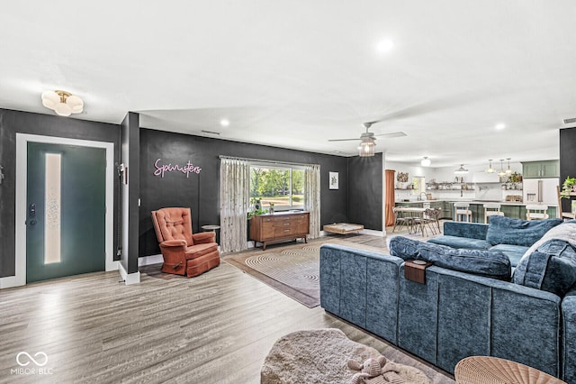 living room featuring light wood-style flooring, a ceiling fan, recessed lighting, and baseboards
