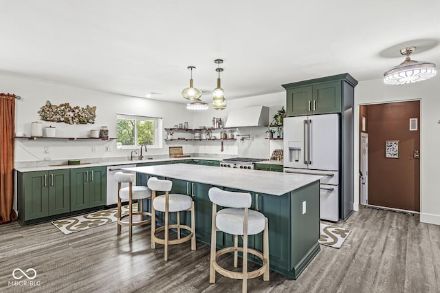 kitchen with green cabinets, white fridge with ice dispenser, open shelves, stainless steel dishwasher, and wall chimney exhaust hood