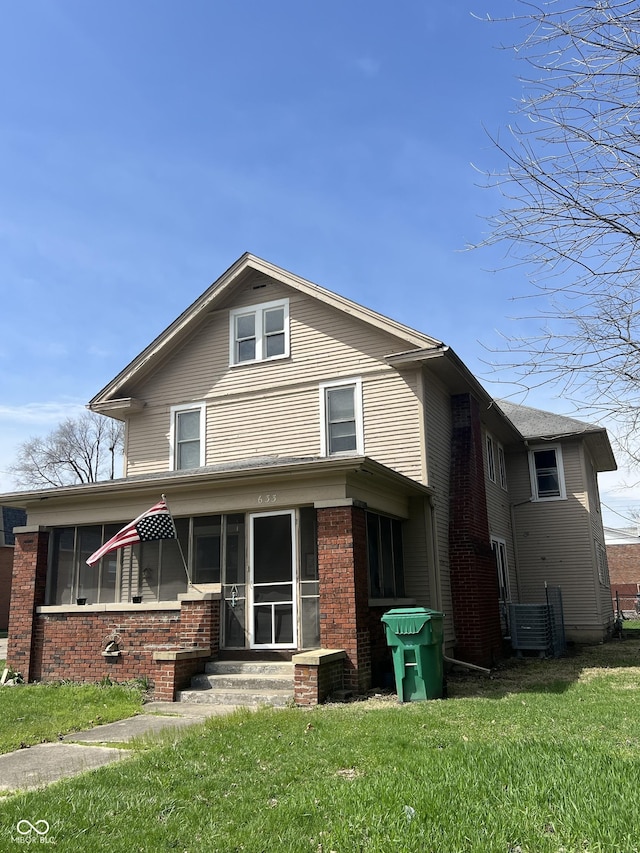 view of front facade with a front lawn, brick siding, and entry steps