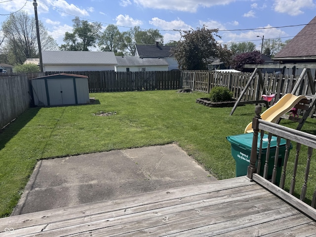 view of yard featuring a shed, an outdoor structure, a playground, and a deck