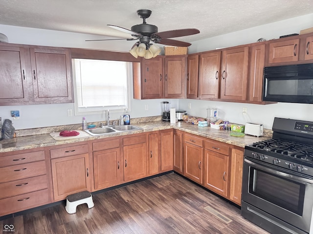 kitchen featuring range with gas cooktop, black microwave, a sink, a ceiling fan, and brown cabinets