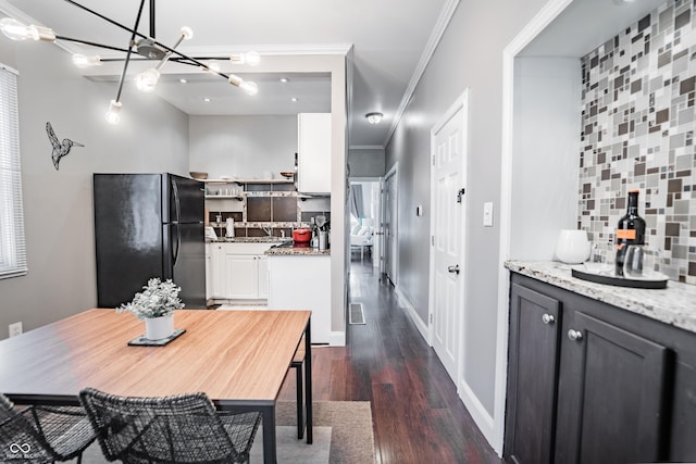 2407 N Capitol Ave, Indianapolis, IN 46208 - dining room featuring dark wood-type flooring, a chandelier, baseboards, and crown molding