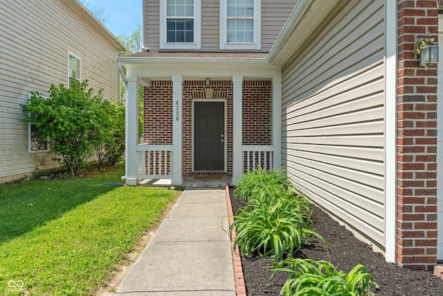 4136 Orchard Valley Ln, Indianapolis, IN 46235 - doorway to property featuring brick siding, a porch, and a yard