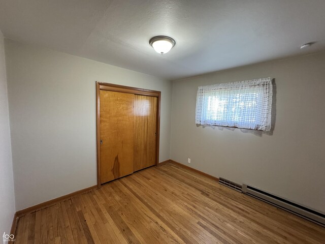 1314 E Orange Pike, Rushville, IN 46173 - unfurnished bedroom featuring light wood finished floors, a closet, and baseboard heating