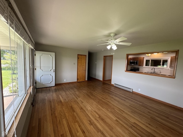 1314 E Orange Pike, Rushville, IN 46173 - unfurnished living room with a baseboard heating unit, wood-type flooring, and ceiling fan