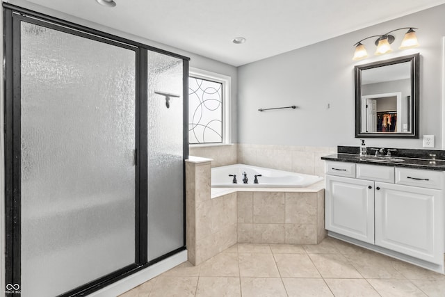 full bathroom with a stall shower, a garden tub, tile patterned flooring, and vanity