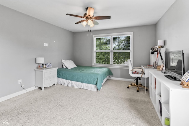 bedroom featuring light carpet, baseboards, a desk, and a ceiling fan