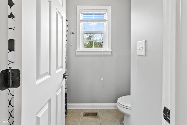 bathroom with baseboards, toilet, and tile patterned flooring