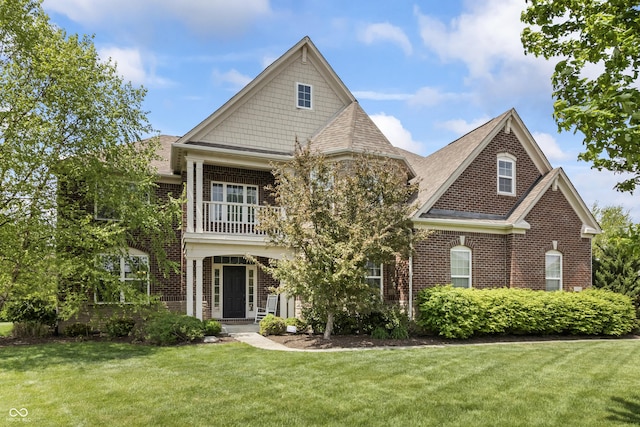view of front facade featuring brick siding, a front lawn, a balcony, and roof with shingles