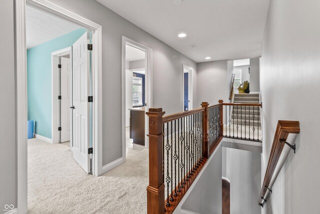 corridor featuring an upstairs landing, baseboards, carpet floors, and recessed lighting