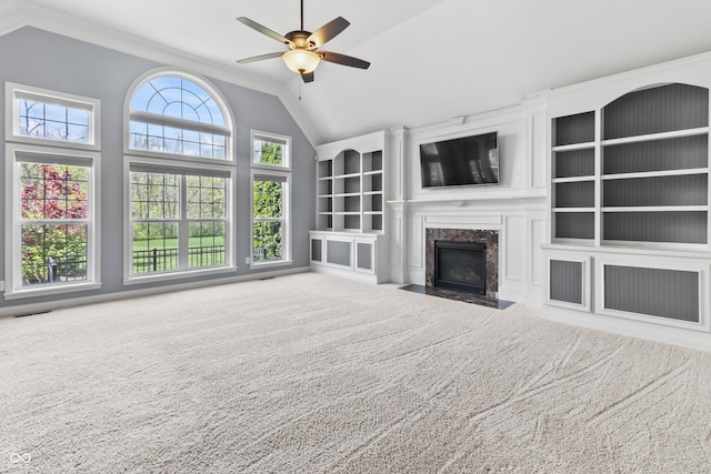 unfurnished living room featuring vaulted ceiling, carpet, ceiling fan, built in features, and a premium fireplace