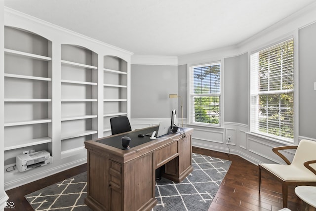 office featuring dark wood-style floors, healthy amount of natural light, a wainscoted wall, built in shelves, and crown molding