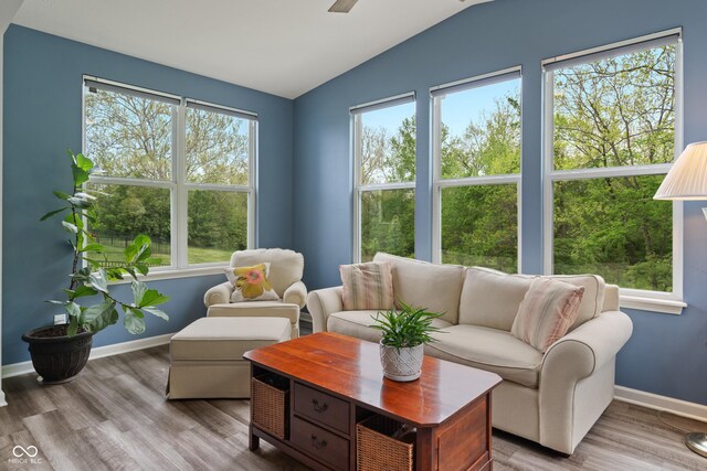 living area with lofted ceiling, wood finished floors, baseboards, and ceiling fan