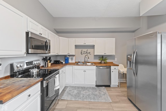 923 S State Ave, Indianapolis, IN 46203 - kitchen featuring butcher block counters, appliances with stainless steel finishes, a sink, white cabinets, and a textured ceiling