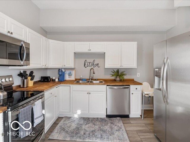 923 S State Ave, Indianapolis, IN 46203 - kitchen with stainless steel appliances, a sink, white cabinetry, light wood-style floors, and wood counters