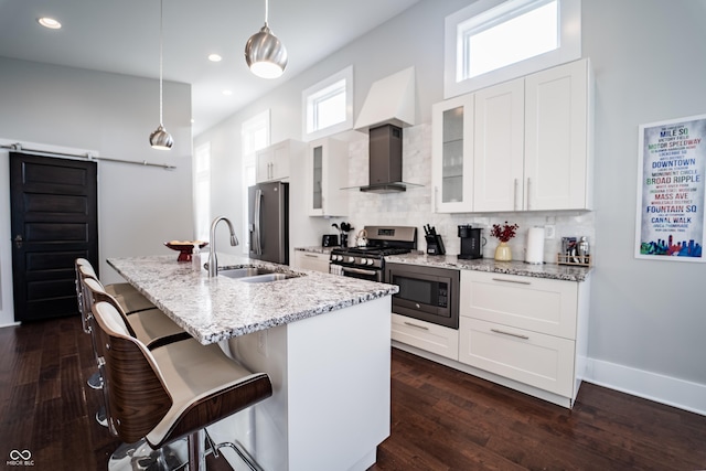 1112 Spann Ave, Indianapolis, IN 46203 - kitchen featuring appliances with stainless steel finishes, wall chimney exhaust hood, a sink, a kitchen island with sink, and a breakfast bar