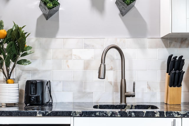 1112 Spann Ave, Indianapolis, IN 46203 - kitchen view of white cabinetry, backsplash, a sink, and dark stone countertops