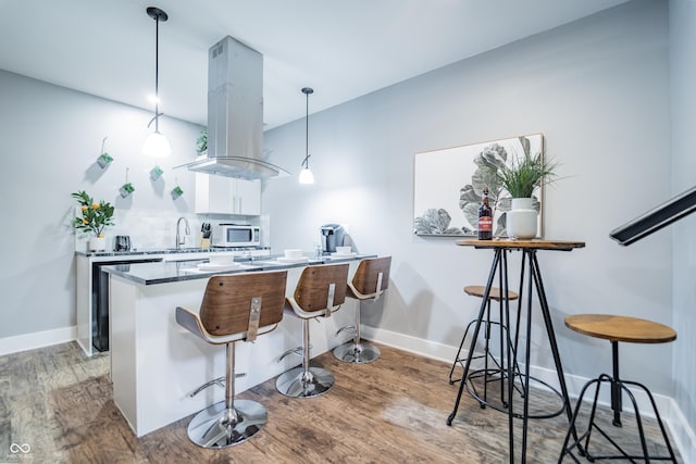 1112 Spann Ave, Indianapolis, IN 46203 - kitchen with island exhaust hood, white microwave, white cabinets, and wood finished floors