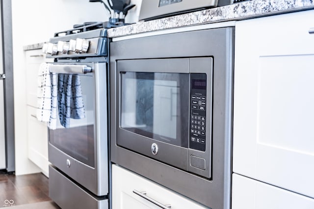 1112 Spann Ave, Indianapolis, IN 46203 - kitchen with stainless steel microwave, white cabinetry, and dark wood-type flooring