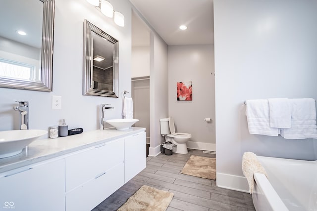 1112 Spann Ave, Indianapolis, IN 46203 - bathroom with wood finished floors, baseboards, a freestanding bath, toilet, and double vanity