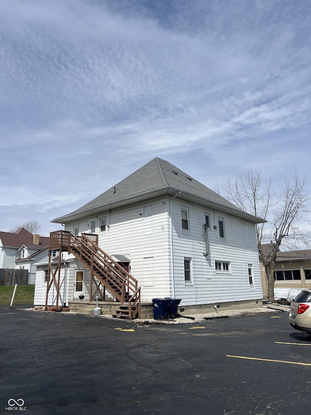 view of side of home featuring stairs and uncovered parking