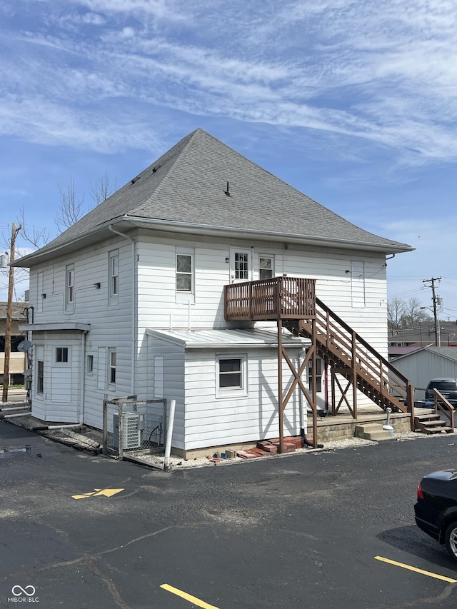 back of house with a shingled roof and stairs