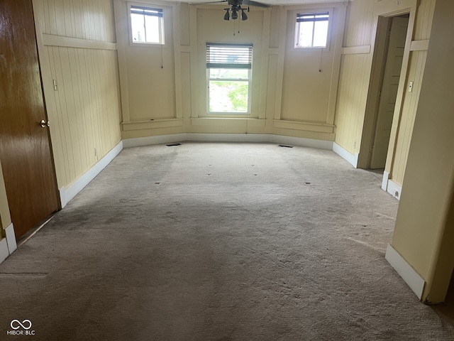 carpeted empty room with a ceiling fan and baseboards