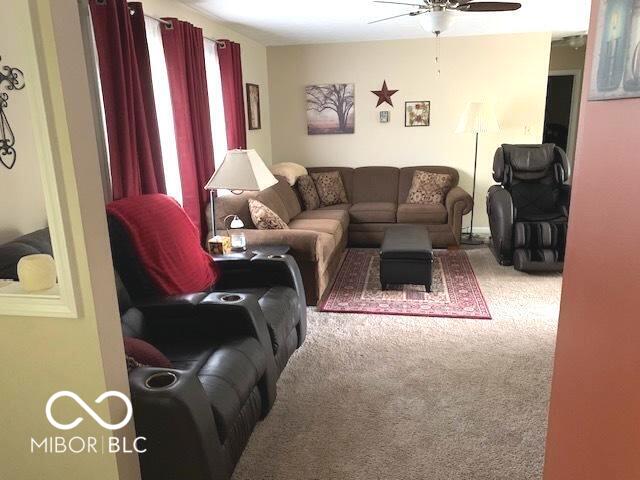 living area with a ceiling fan and carpet