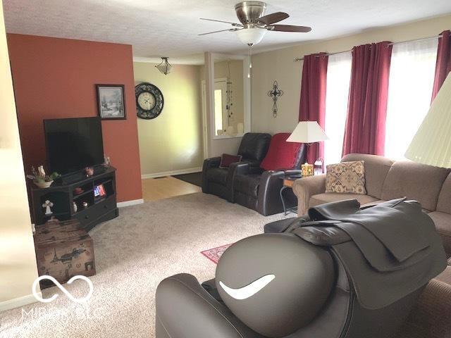 carpeted living area featuring baseboards and ceiling fan