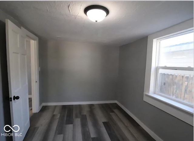 spare room featuring baseboards and wood finished floors