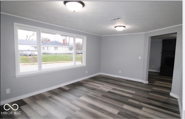 empty room with baseboards, a fireplace, visible vents, and dark wood-type flooring