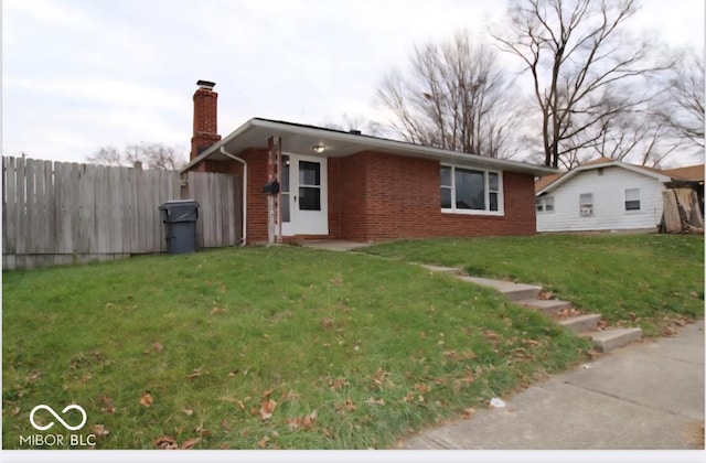 view of front of house featuring a chimney, brick siding, a front lawn, and fence