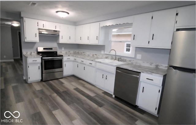 kitchen with under cabinet range hood, white cabinetry, appliances with stainless steel finishes, and a sink