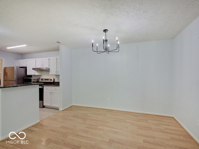 unfurnished dining area featuring light wood-type flooring, a chandelier, a textured ceiling, and baseboards