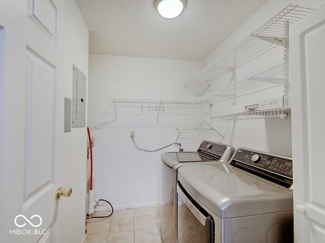 washroom featuring independent washer and dryer, electric panel, baseboards, light tile patterned floors, and a textured ceiling