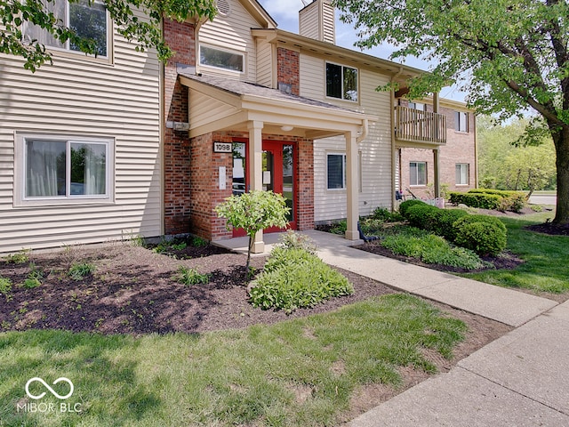 view of front of home with a chimney and brick siding