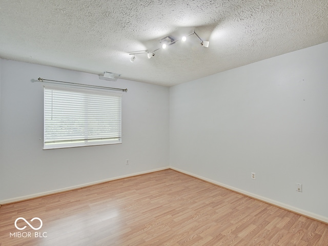 spare room featuring wood finished floors, a textured ceiling, and baseboards