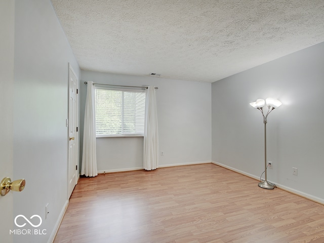 unfurnished room with light wood-type flooring, a textured ceiling, and baseboards