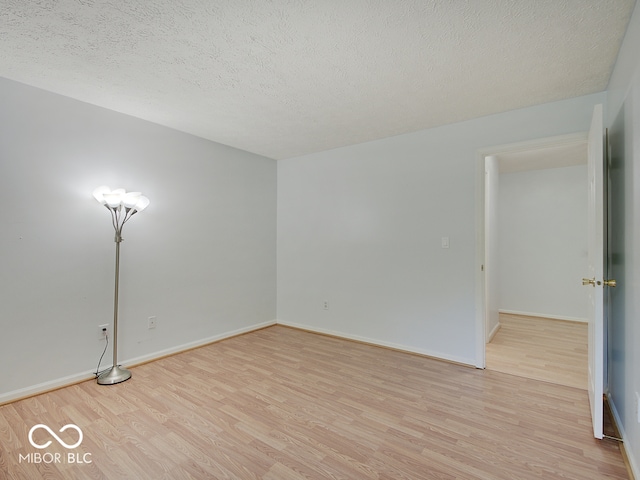 unfurnished room featuring light wood-style floors, a textured ceiling, and baseboards